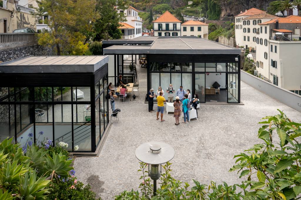 Vista aérea do espaço de co-working da Digital Nomads, com construções de vidro e jovens a conversar do lado de fora