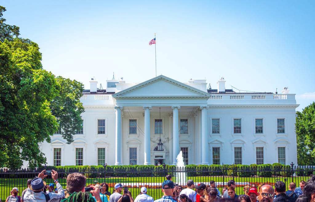 Turistas posam para fotos em frente aos portões que cercam a Casa Branca, em Washington D.C.