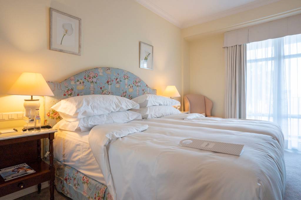 155 Quarto do hotel Reid's Palace, na Ilha da Madeira, com detalhe da cama com travesseiros, edredons e a cabeceira azul florida