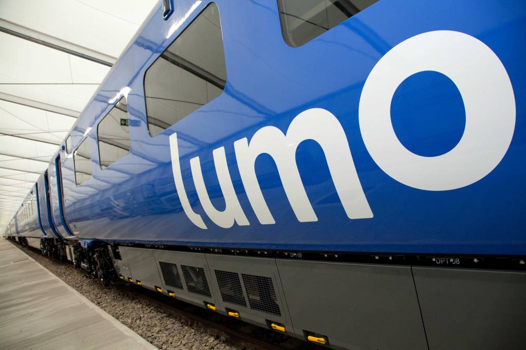 A imagem é a foto da lateral de um trem azul com seu logo escrito lumo