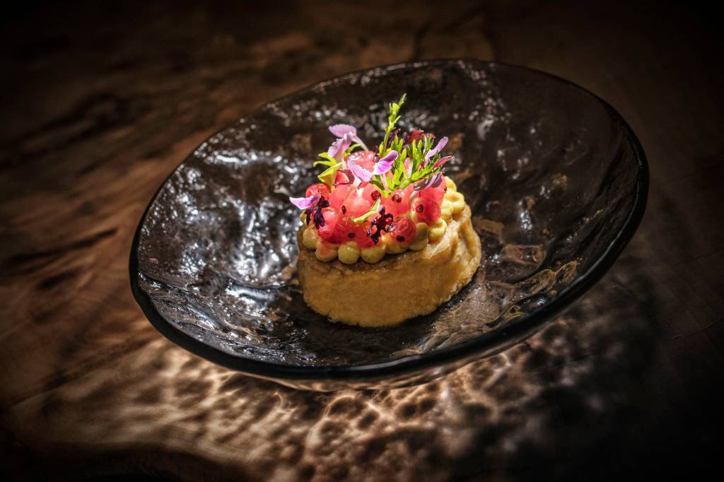 Prato de vidro com um prato moderninho de panqueca com pequenas cerejas em cima