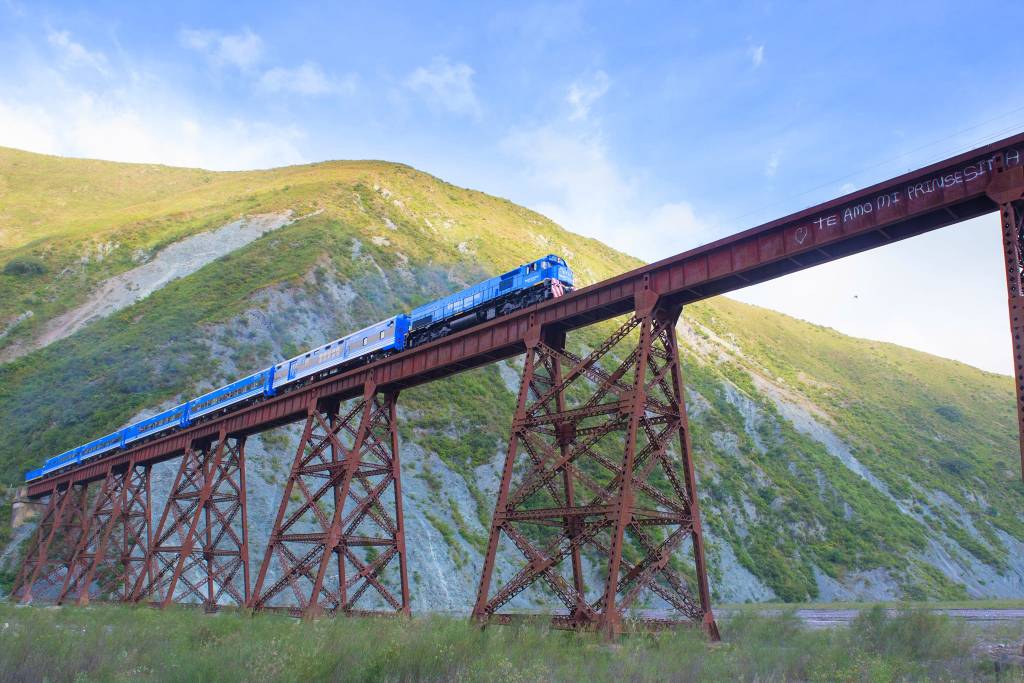 Na imagem, um trem passa sobre uma ponte muito alta.