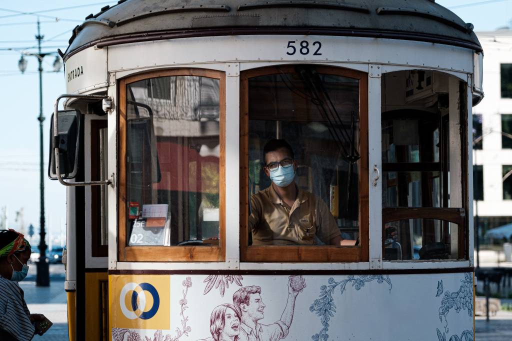 Elétrico (antigo bonde) com detalhes em madeira em Lisboa, com o motorista usando máscara contra a infecção por covid-19