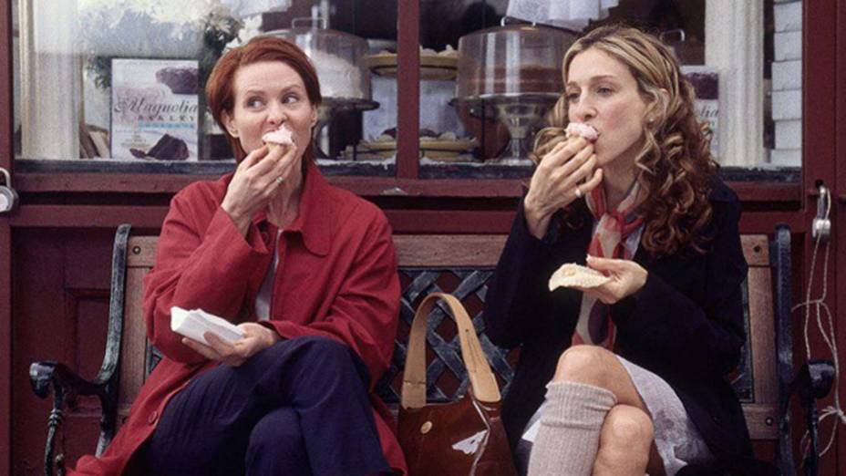 Miranda e Carrie devorando cupcakes no banco em frente à Magnolia Bakery.