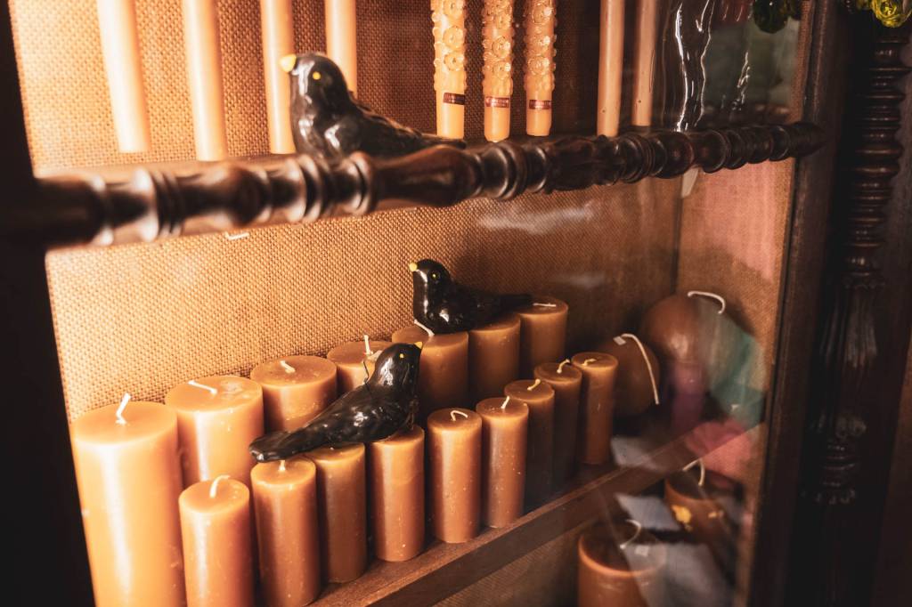 Detalhe de uma prateleira antiga de uma loja, com velas e andorinhas de cerâmica
