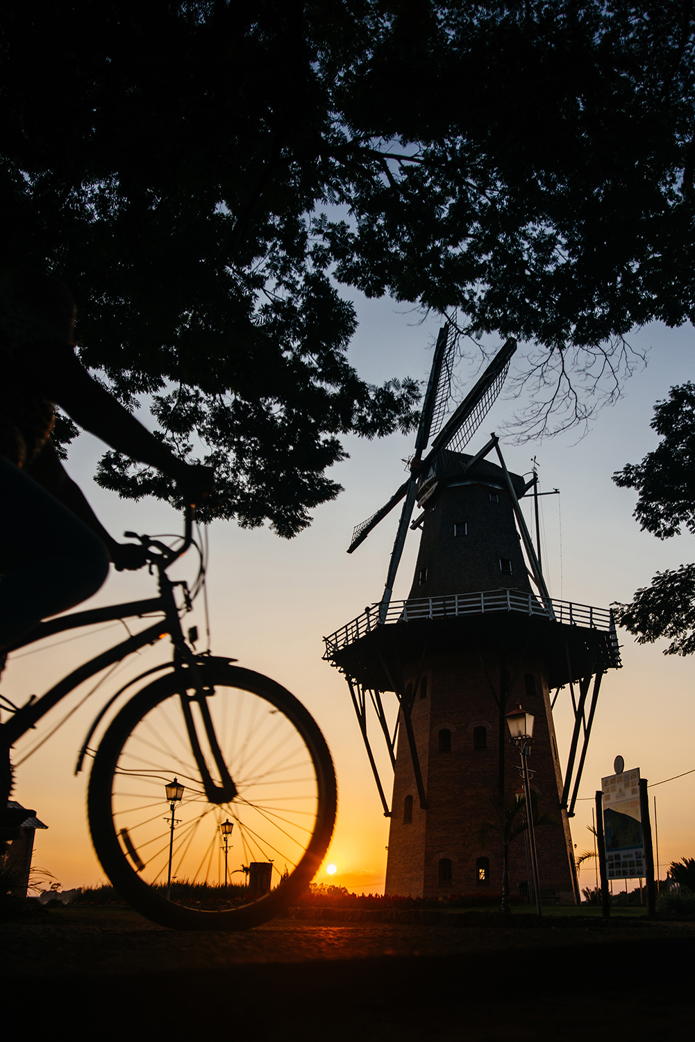 A imagem está contra a luza. Mas é possível ver a silhueta de uma bicicleta e de um moinho.