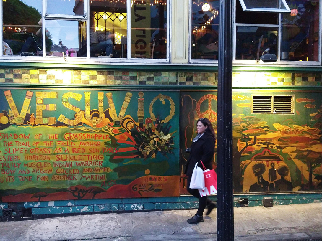 Graffiti extremamente colorido na lateral do bar Vesúvio com uma mulher de cabelos pretos andando.