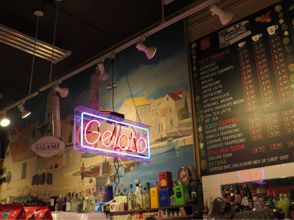 Luminoso escrito GELATO e cardápio de parede em forma de lousa em segundo plano