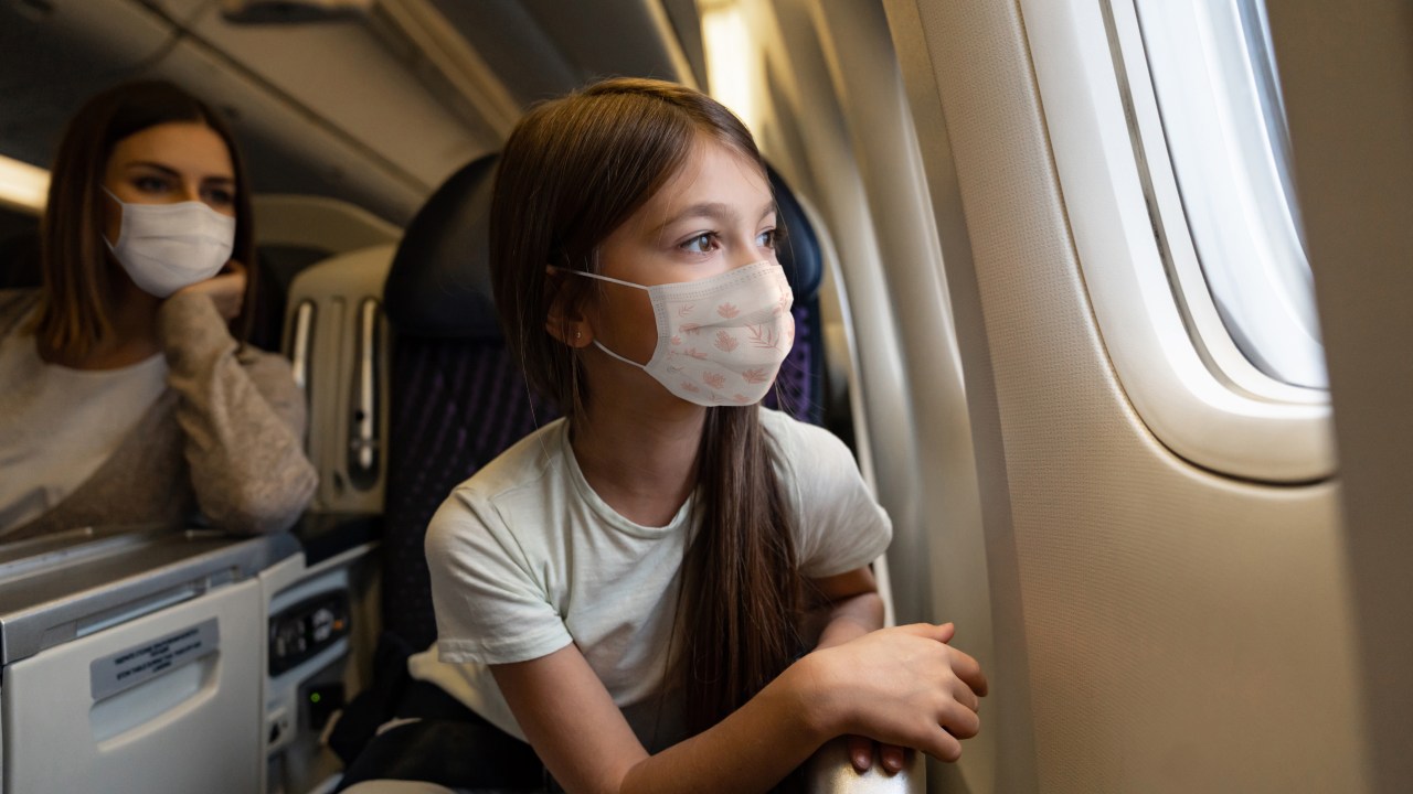 Criança usando máscara em viagem de avião