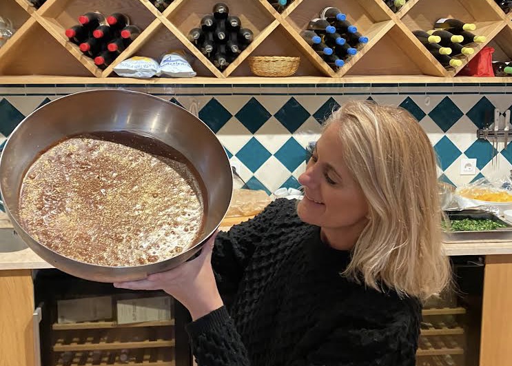 Uma mulher loira de blusa preta mostra o seu grande pote de mousse de chocolate