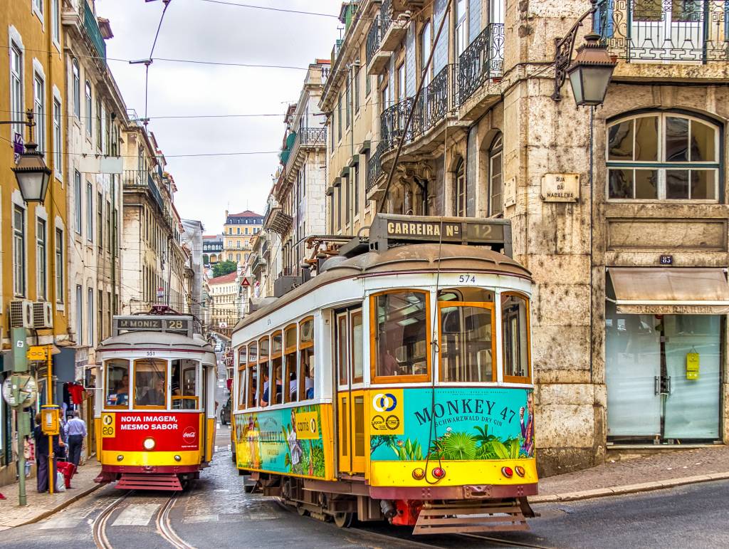 Dois bondinhos coloridos circulando pelas ruas do centro histórico de Lisboa