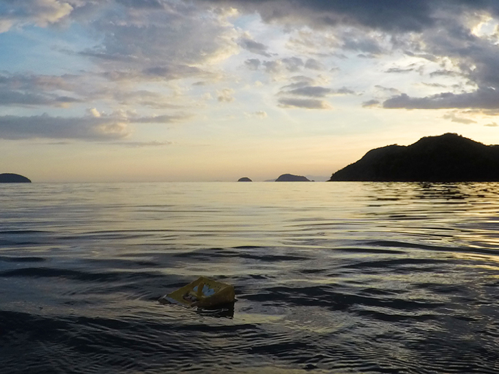 Um boneco do Bob Esponja boia nas águas do mar. Ao fundo um por do sol!