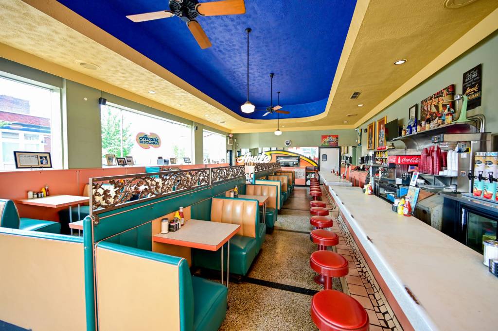 A imagem mostra o interior de um restaurante antigo com móveis em várias cores, como verde, vermelho, azul e amarelo.