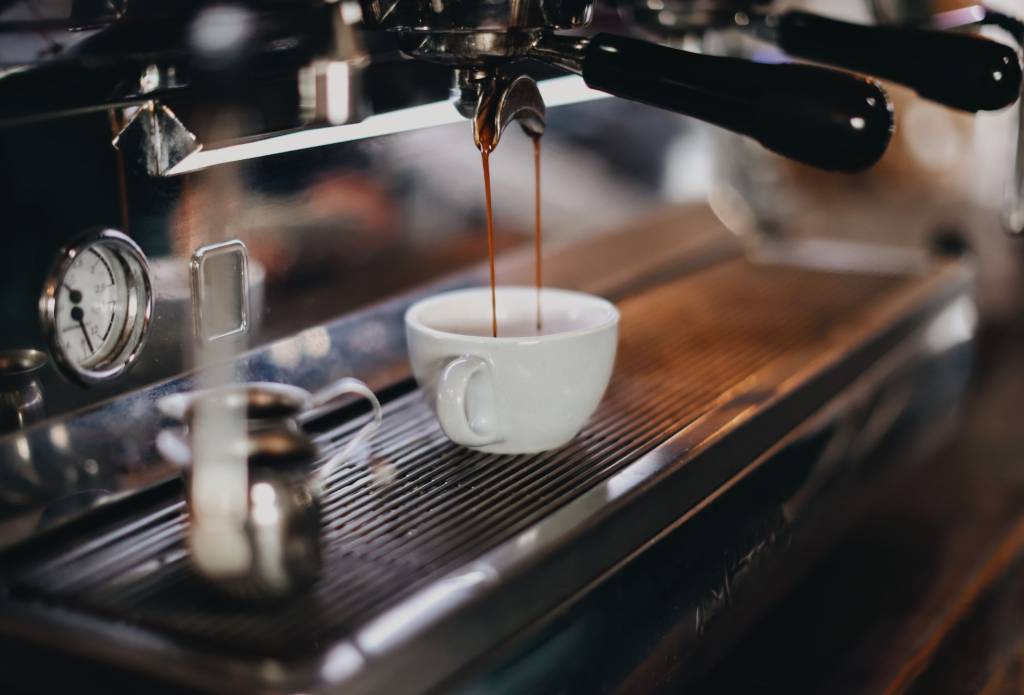 Uma máquina de café expresso enchendo uma xícara de café branca