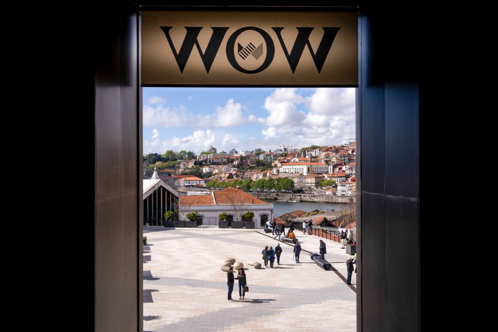 Vista de uma janela onde lê-se WOW e vê-se um pátio e a cidade do Porto ao fundo