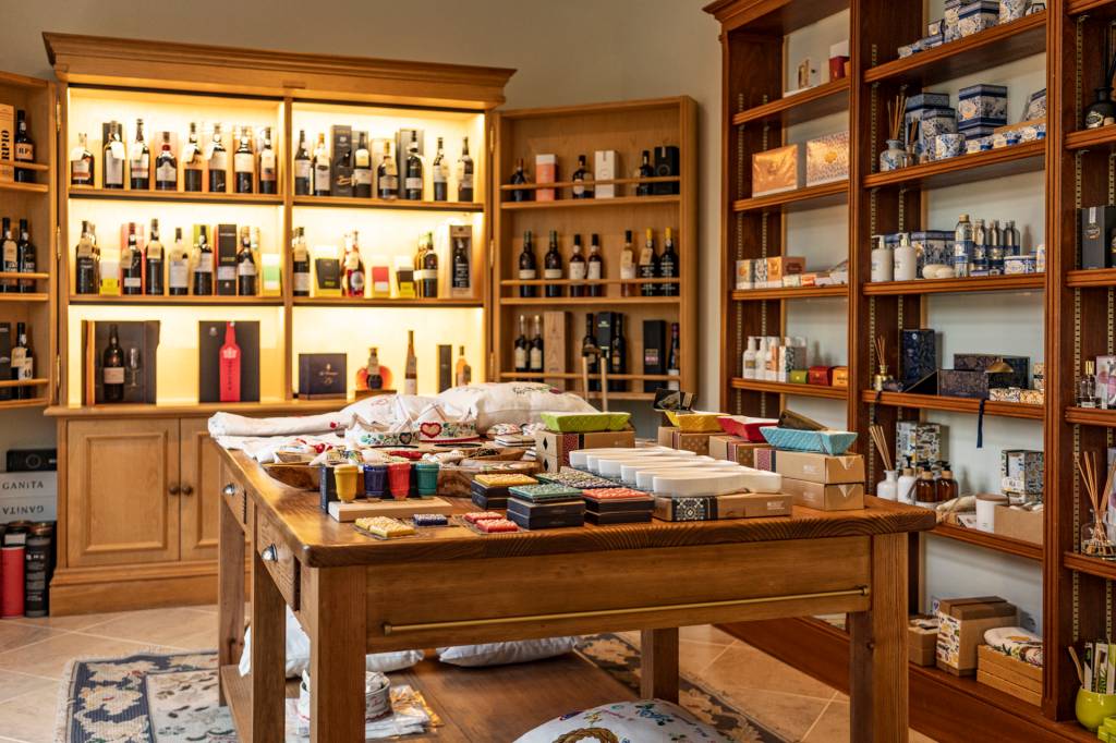 13 Bancada e prateleiras de uma loja recheadas de garrafas de vinho e caixinhas coloridas