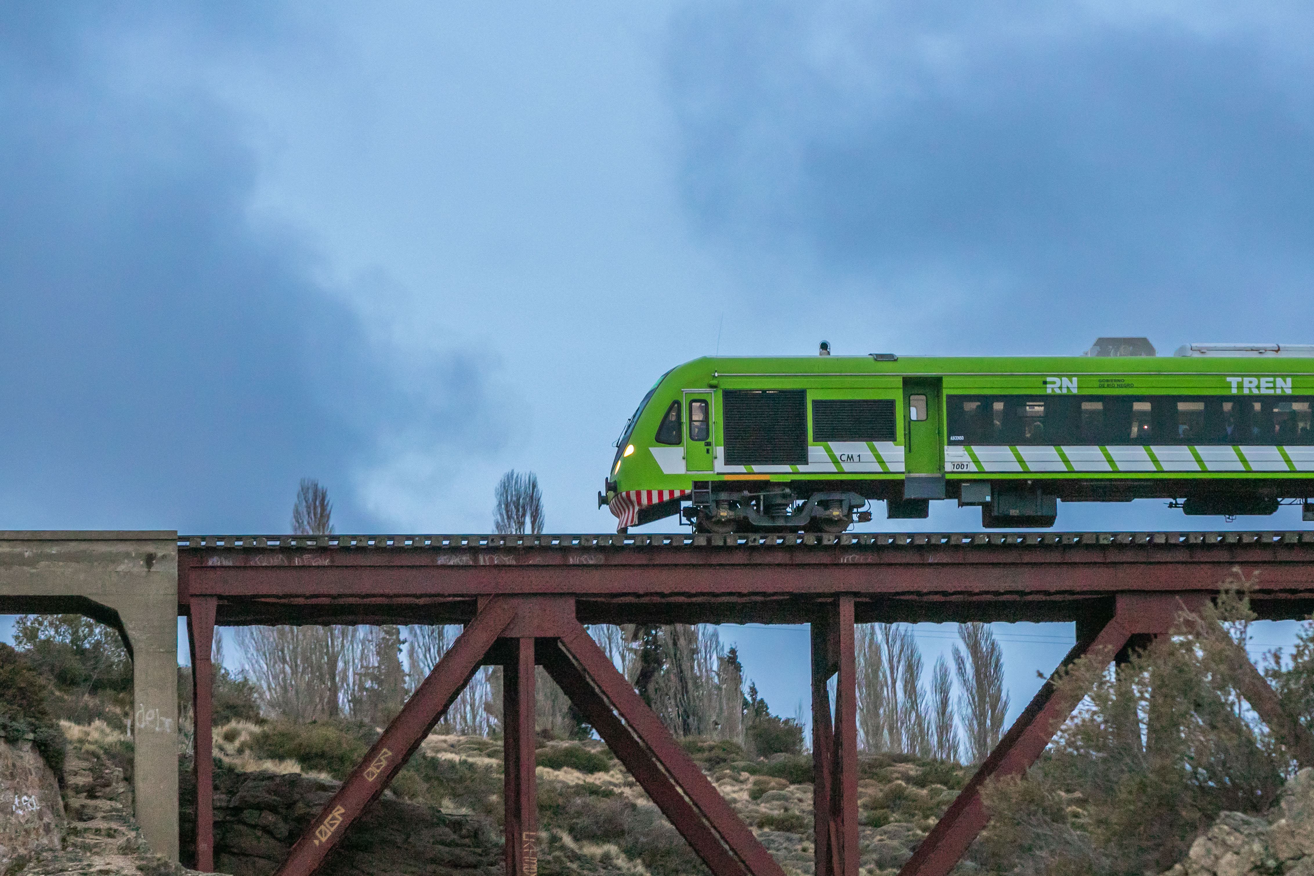 A imagem mostra um trem verde fazendo um trajeto noturno