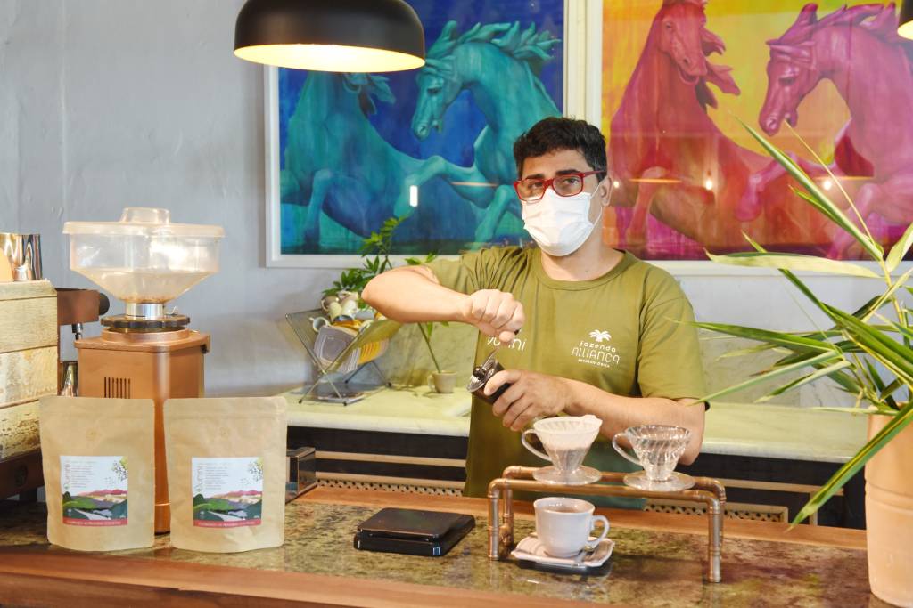 A imagem mostra um homem branco fazendo café