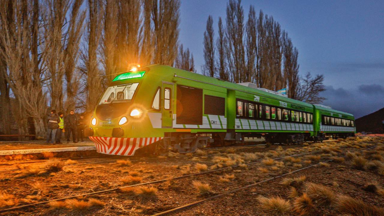 A imagem mostra um trem verde fazendo um trajeto noturno