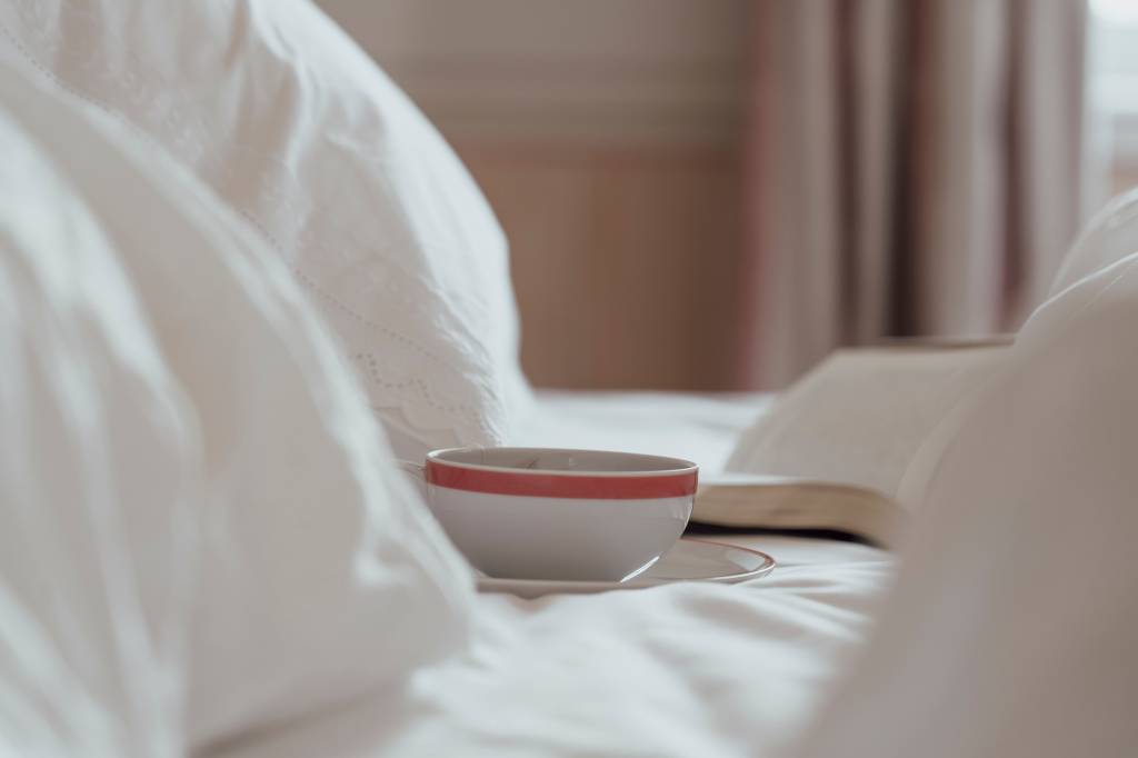 Xícara de chá e livro sobre a cama desarrumada