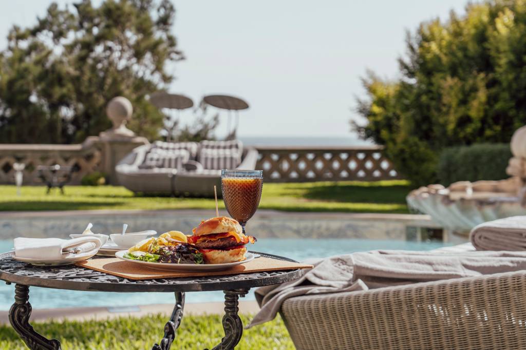 Hamburguer e suco de frutas vermelhas servidos à beira da piscina