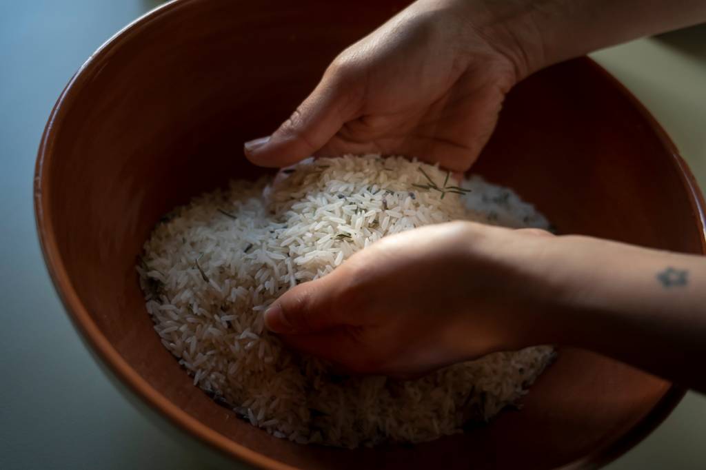 Um bowl de cerâmica com grãos de arroz e ervas para tratamentos no spa