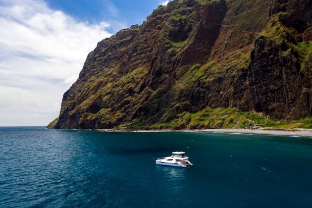 Barco parado nos arredores de uma ilha de grandes falésias