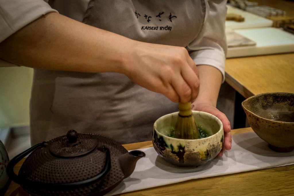 Chef prepara o matchá, chá japonês, macerando os ingredientes em uma cumbuca