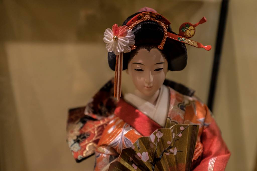 Pequena escultura de uma gueixa a caráter, vestida de kimono e com enfeites no cabelo