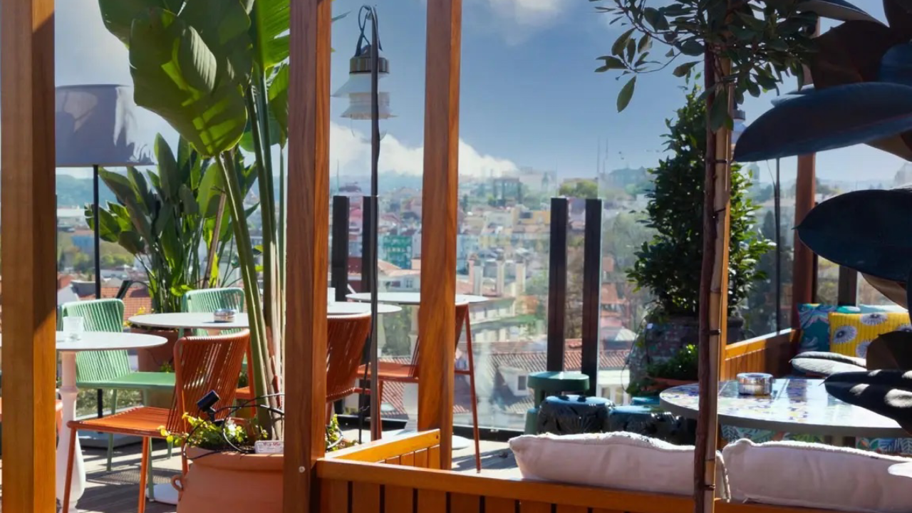 Mesas de madeira e plantas em um terraço do hotel Mama Shelter em Lisboa