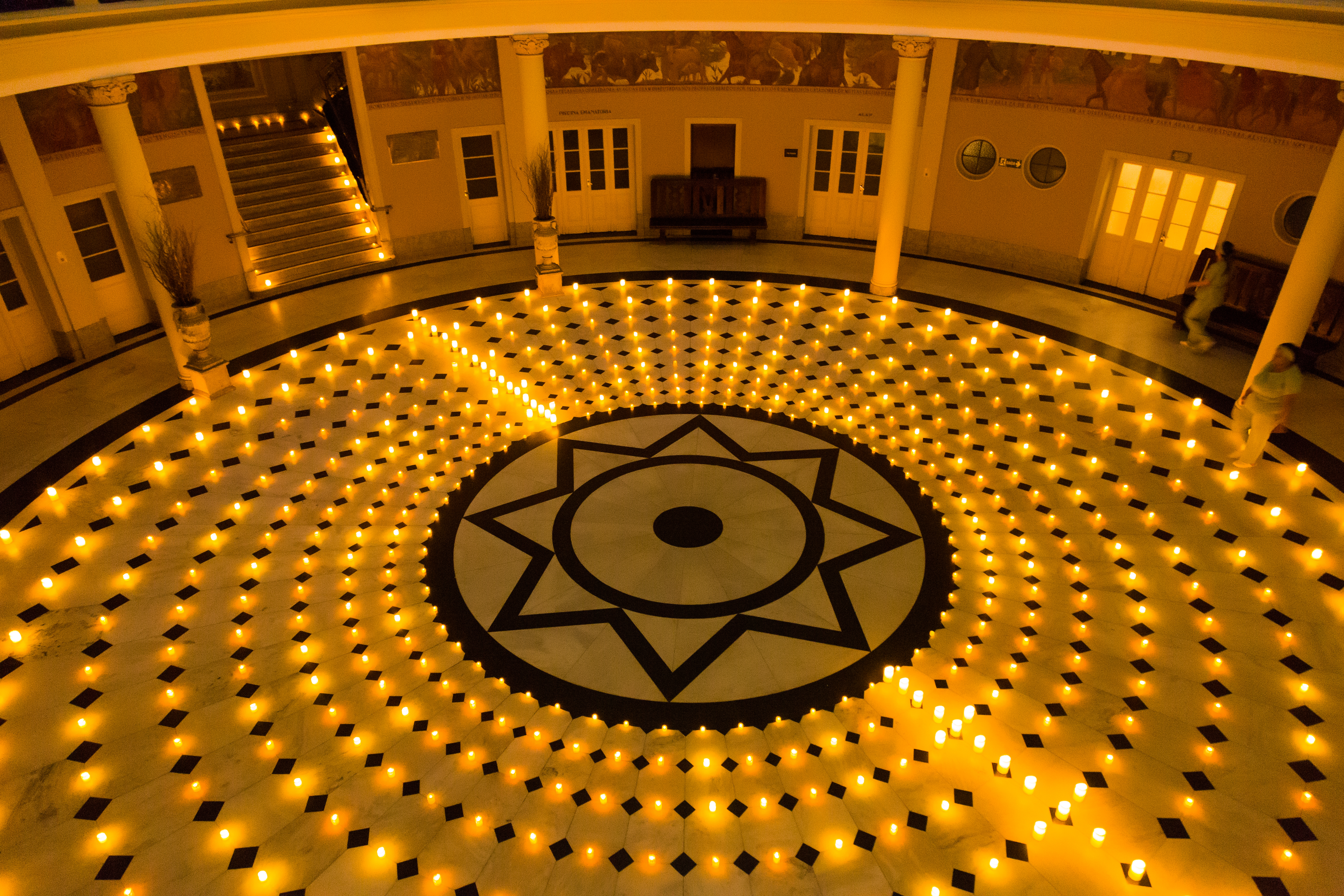 A fotografia mostra velas dispostas em círculo no chão