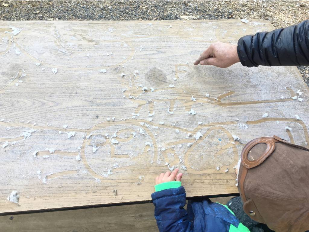 Mãos de criança e adulto, desenhando sobre uma mesa coberta de gelo fino