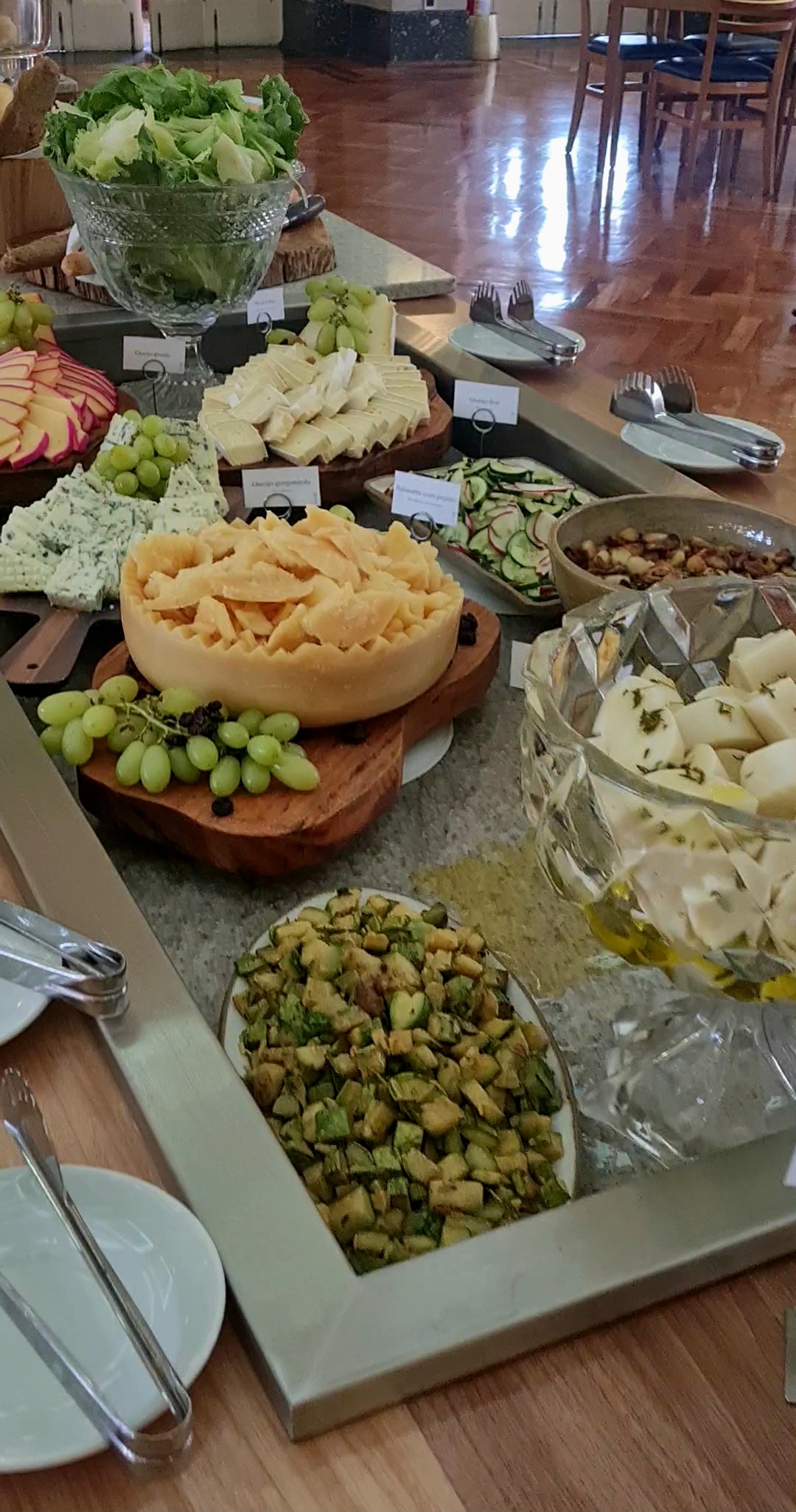 A foto mostra uma mesa com queijos e verduras