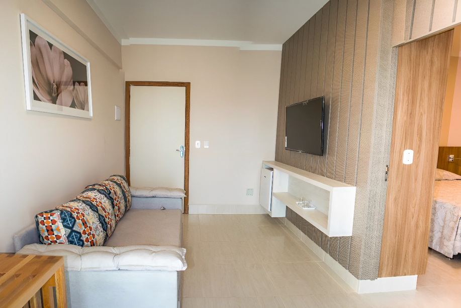 A fotografia mostra uma foto de uma sala com parede de madeira e sofá-cama estampado