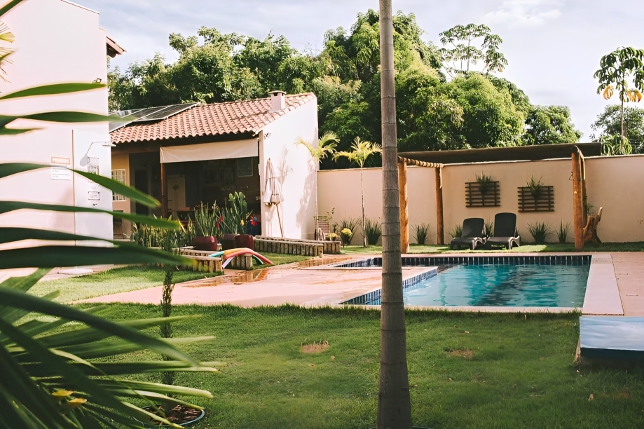 A imagem mostra um jardim com gramado e uma piscina