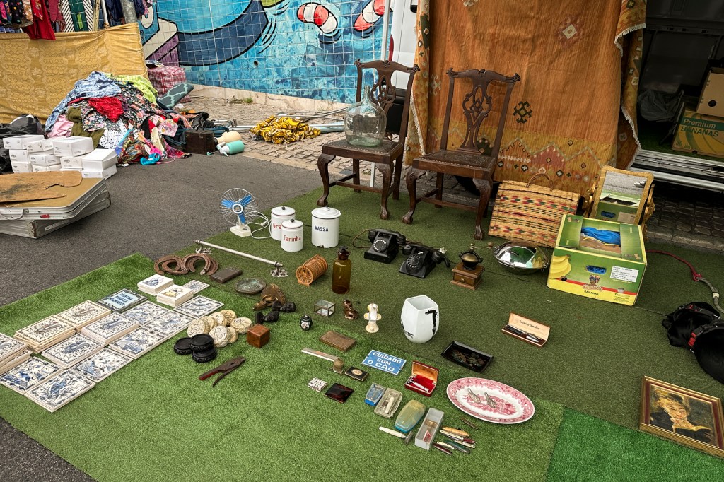 Objetos variados expostos no chão de numa barraca da Feira da Ladra em Lisboa