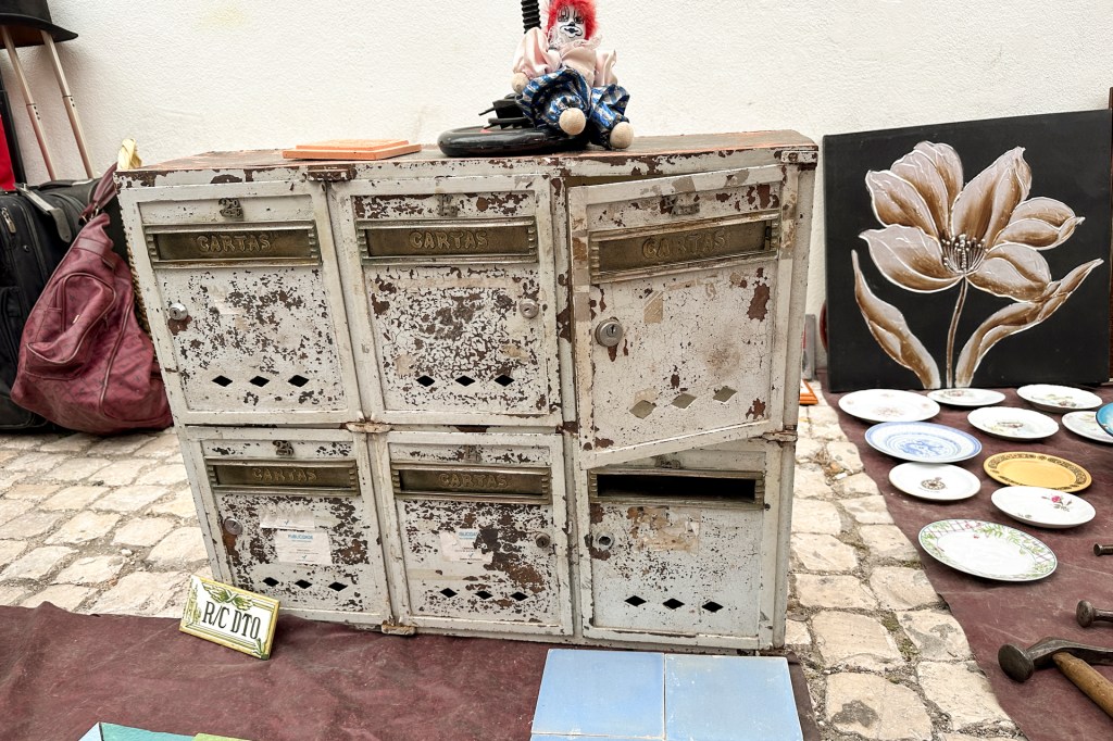 Uma caixa de correios antiga, de metal, enferrujada, com seis portas, em exposição na Feira da Ladra