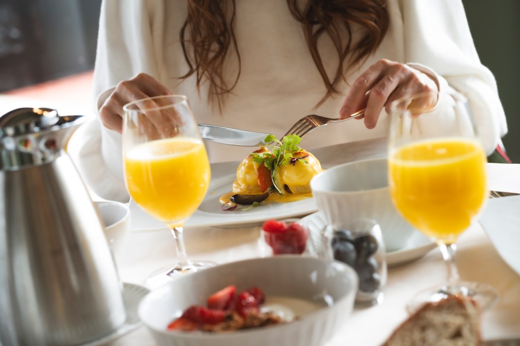 Mesa de café da manhã com ovos, suco de laranja e iogurte com frutas vermelhas