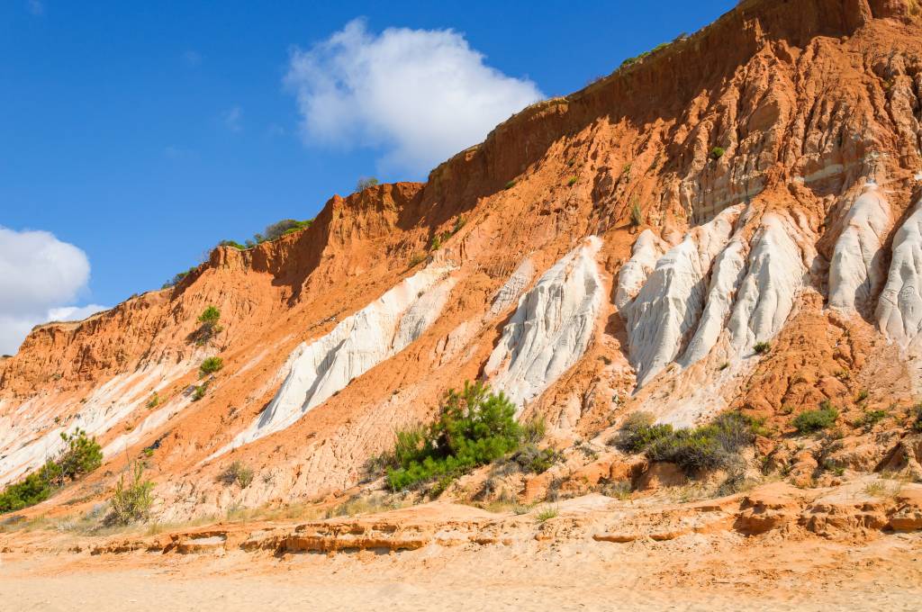 Red cliffs at Falesia Beach Foto colorida mostra falésias alaranjadas e brancas de quase 40 metros de altura numa praia em Portugal