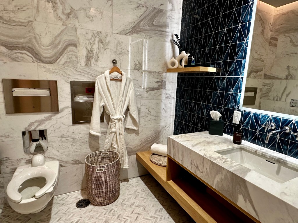 Banheiro espaçoso e mimos à postos Delta One Lounge