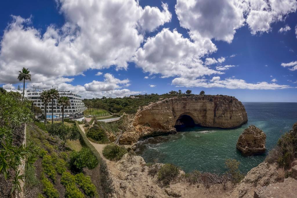 Paisagem com o mar verde embaixo, cercado por uma falésia, onde está construído o hotel