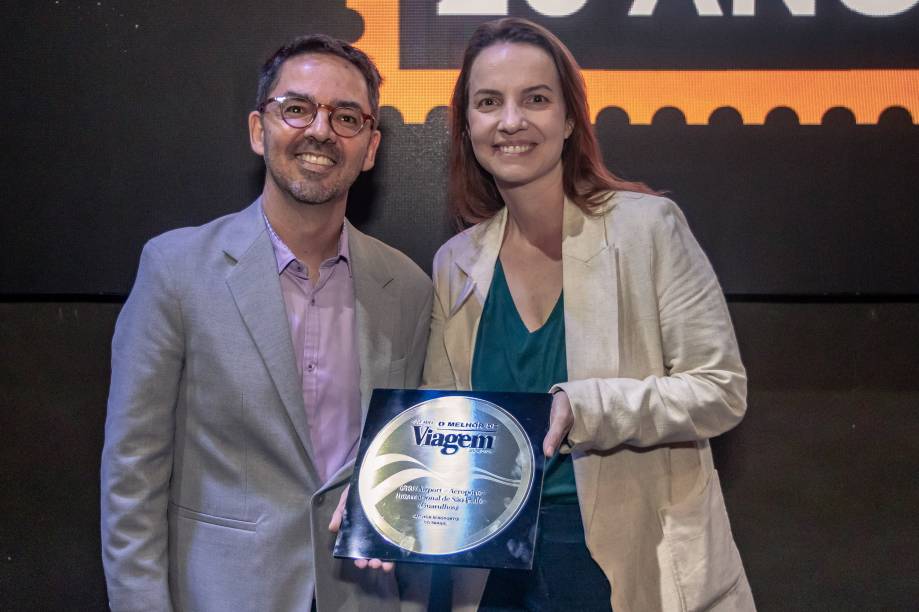 Julia Orrico, gerente de negócios aéreos do Aeroporto de Guarulhos, com o prêmio de melhor da categoria. Ao lado, Fabrício Brasiliense, da VT