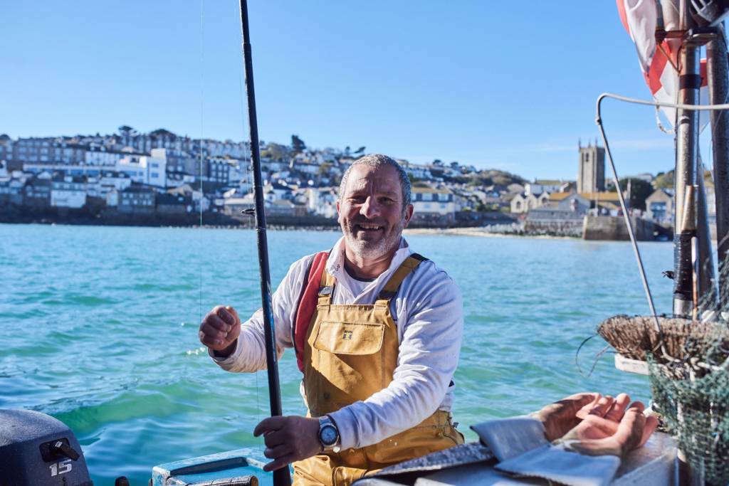 Fisherman in his fishing boat in the harbour, St. Ives, Cornwall, England. Fisherman in his fishing boat in the harbour, St. Ives, Cornwall, England.