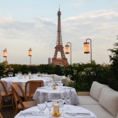 Terraço com mesas e cadeiras, com vista para a Torre Eiffel